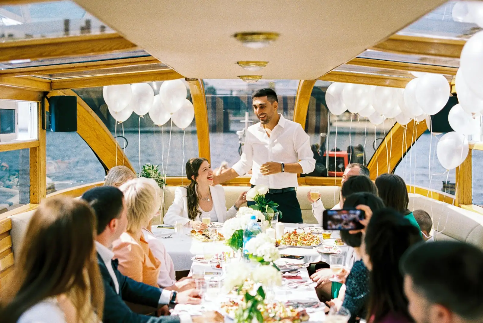 Groom giving a speech to wedding guests seated around a celebratory table